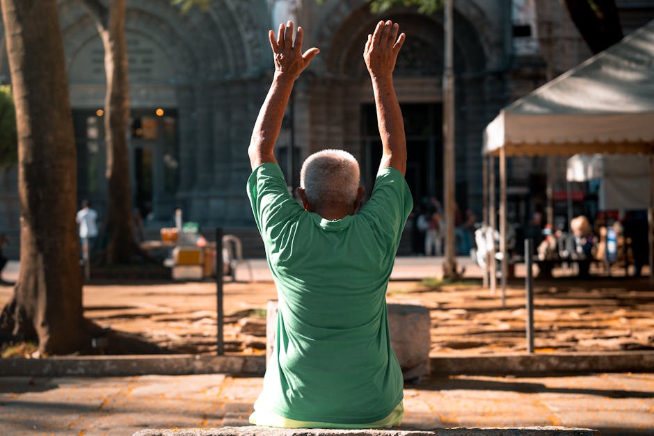 A senior man raises his arms during a sunny day outdoors in Manila.