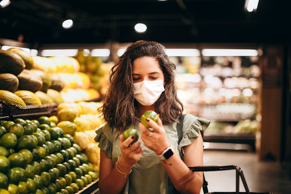 Woman wearing mask selecting fresh produce in a supermarket aisle.