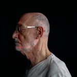 Side profile of a senior man with facial recognition scan lines on a plain black background.