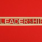 Wooden letters spelling leadership on a vibrant red background, conveying bold concepts.