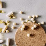 A mix of various capsules and pills scattered on a cork surface, depicting healthcare and wellness.