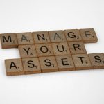 Wooden tiles spelling 'Manage Your Assets' offer conceptual business advice.